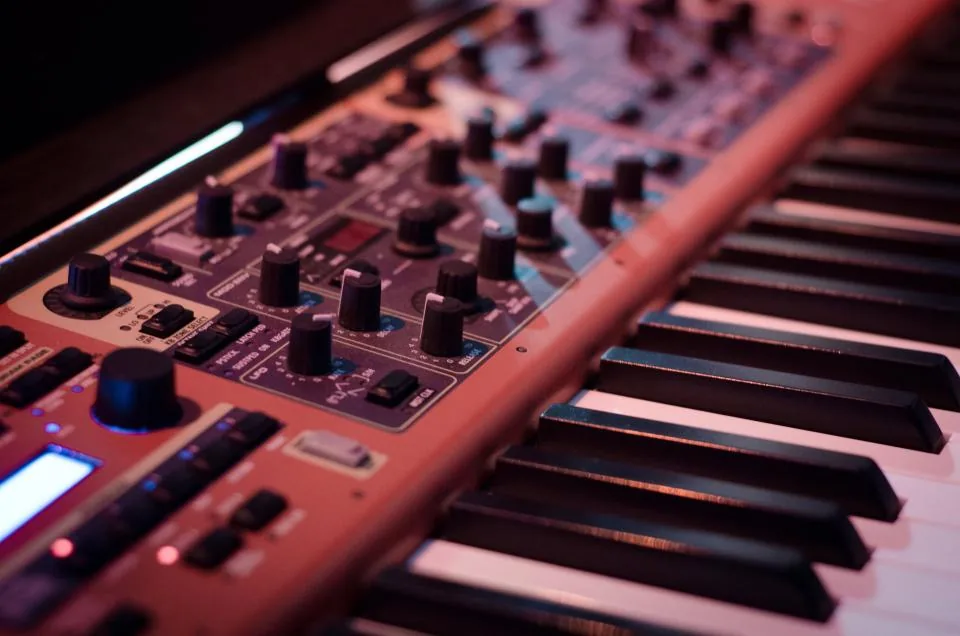 Close-up of a synthesizer keyboard's control panel — knobs, sliders, and piano keys
