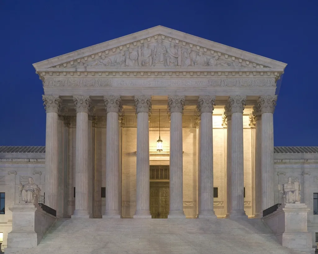 The floodlit columned facade of the U.S. Supreme Court Building at dusk
